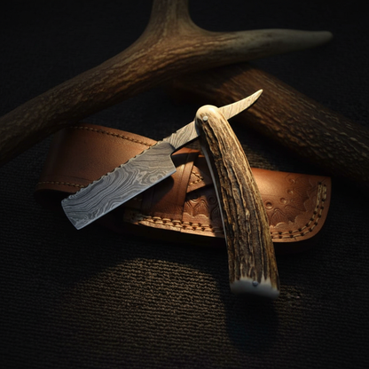 Handmade Damascus straight razor with antler handle and leather sheath display on dark background