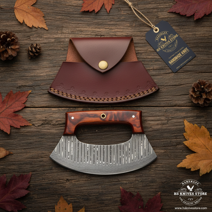 Damascus ulu knife flat lay with tortoiseshell resin handle and HS Knives Store hang tag on rustic dark wood with autumn leaves
