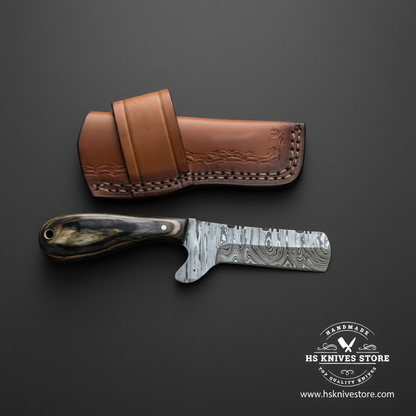 Damascus bull cutter cowboy knife with pakkawood handle and steel bolster on dark charcoal studio background facing right