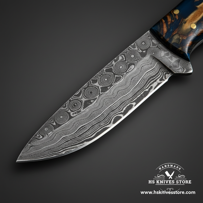 Close-up of Damascus steel skinner knife blade showing unique circular eye-shaped Damascus pattern and polished cutting edge macro detail