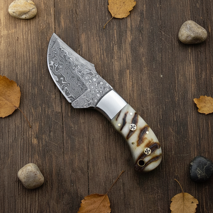 Handmade Damascus skinner knife with ram horn handle flat lay on rustic dark wood surface