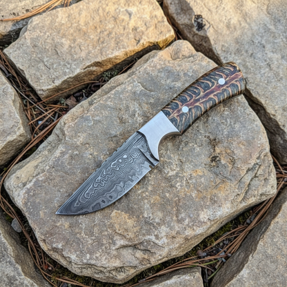 Handmade Damascus skinner knife pinecone resin handle on natural stone outdoors