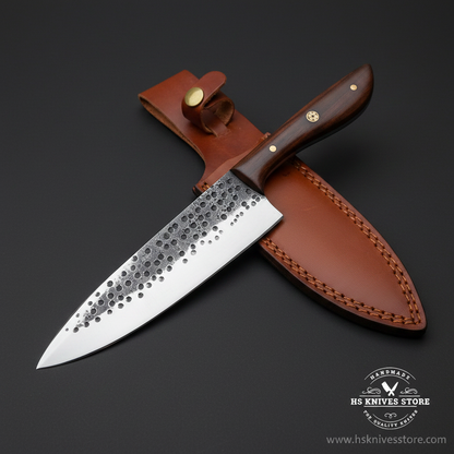 Carbon steel chef knife with hammered blade and walnut handle and tan leather sheath mirror view on dark charcoal background