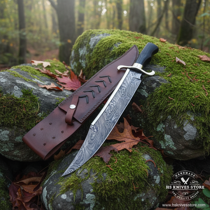 Damascus steel large Bowie knife resting on mossy rocks in outdoor forest setting with chevron leather sheath