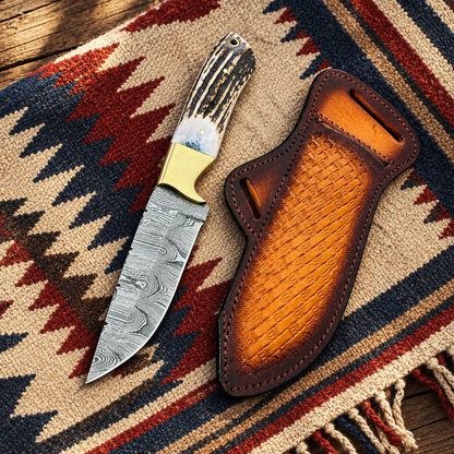 Top-down view of Cowboy Champion Damascus Knife and its matching leather sheath on a western blanket