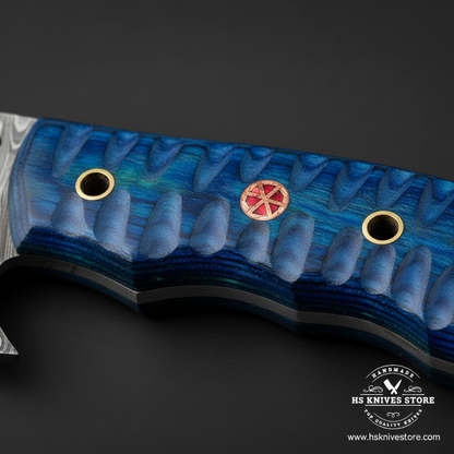 Macro close-up of deep royal blue pakkawood handle with textured grain 3 steel pins and red copper mosaic medallion on Damascus tracker knife