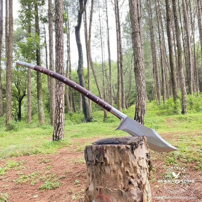Single fantasy spear propped against a tree stump in a bright forest setting