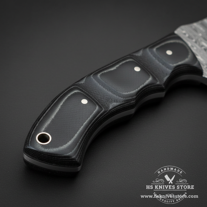 Macro view of black Micarta handle with gray liner, two silver pins and lanyard hole on Damascus tracker knife