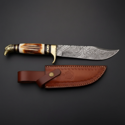 Hand forged Damascus Bowie knife with white burned bone handle and eagle pommel, dark charcoal studio background