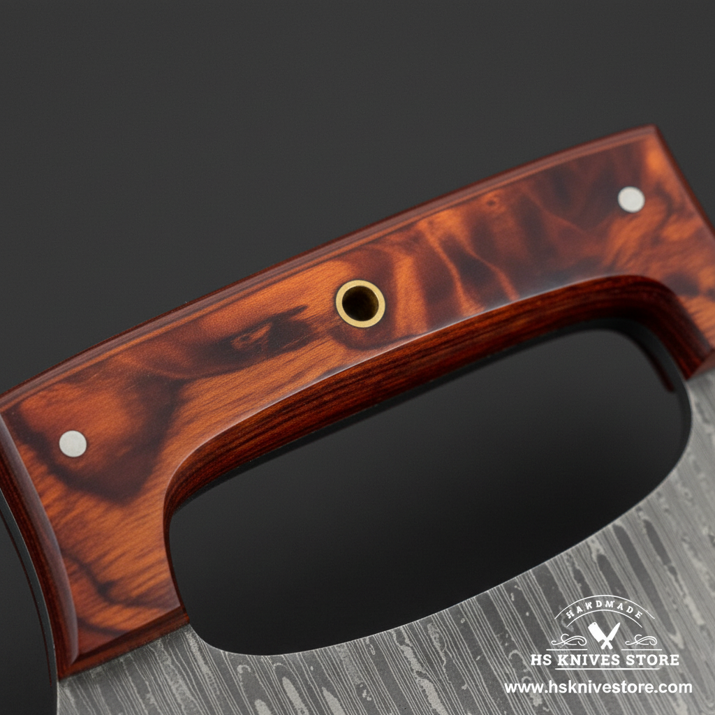 Macro view of tortoiseshell amber resin handle with open finger loop brass eyelet and silver pins on Damascus ulu knife