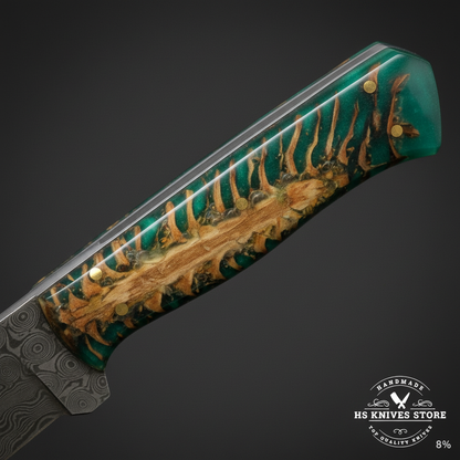 Macro view of emerald green resin handle with natural pine cone inlay visible through resin and brass pin on Damascus skinner knife