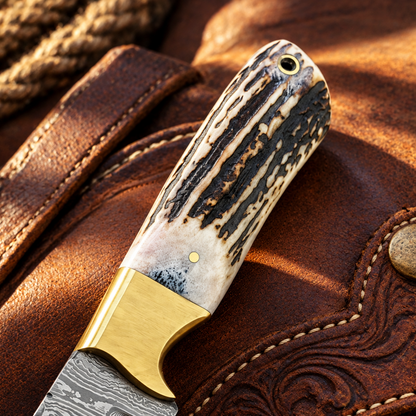 Close-up showing natural antler horn handle texture and brass bolster on Cowboy Champion Damascus Knife