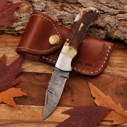 Damascus back lock folding knife with stag handle flat lay on rustic wood surface with leather belt sheath