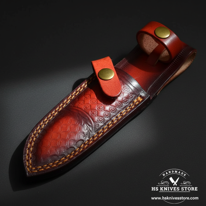 Close-up of dark burgundy wine red leather knife sheath with embossed pattern and bright red orange belt loop panel and brass snap button