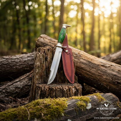 D2 steel Bowie knife green pakkawood handle resting on mossy rocks in outdoor forest setting with tan leather sheath golden sunlight