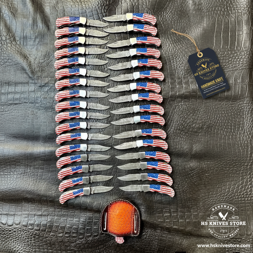 35 Damascus pocket knives USA flag handles herringbone fan pattern flat lay with HS Knives Store hang tag on dark crocodile leather