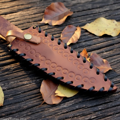 Brown leather knife sheath with embossed circle pattern and black lace stitching detail macro shot
