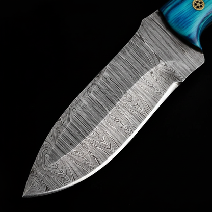 Extreme macro close-up of Damascus steel skinner knife blade showing bold ladder twist Damascus pattern and razor sharp drop point edge