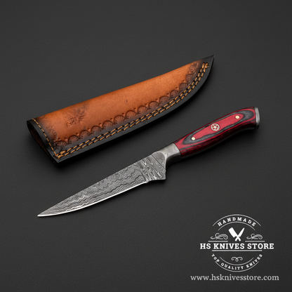 Damascus steel skinning knife with red crimson hardwood handle and two-tone leather sheath on dark charcoal background studio shot