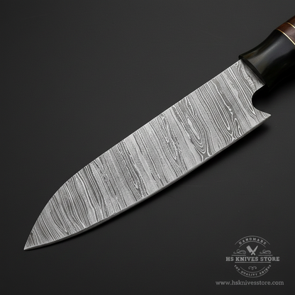 Close-up of Damascus steel chef knife blade showing layered wood-grain Damascus pattern and kiritsuke profile