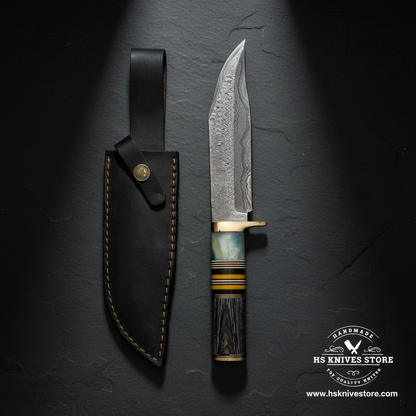 Damascus Bowie knife displayed vertically on dark slate with abalone horn handle and black leather sheath luxury shot