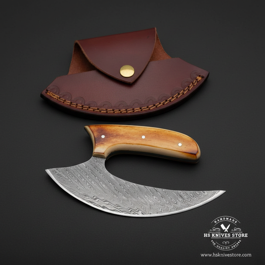Damascus ulu knife with amber bone handle steel bolster and burgundy crescent leather sheath on dark charcoal studio background facing right