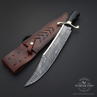 Damascus steel large Bowie knife brass crossguard black hardwood handle chevron leather sheath dark charcoal studio background