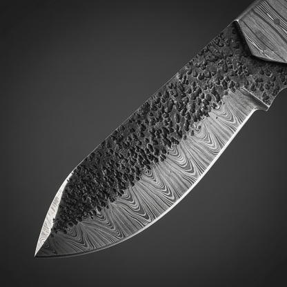 Damascus steel blade close-up showing hammered spine texture and flowing layered Damascus pattern