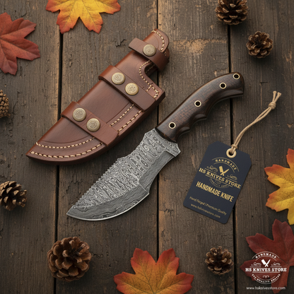 Damascus tracker knife flat lay with micarta handle and HS Knives Store hang tag on rustic wood with autumn leaves