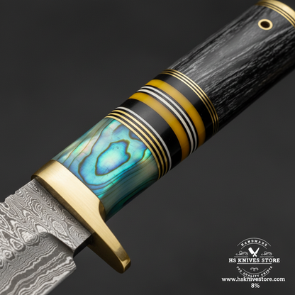 Macro view of three-section handle showing iridescent abalone resin spacer rings and dark horn cap on Damascus Bowie knife