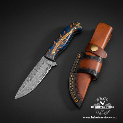 Damascus skinner knife with blue resin pine cone handle and two-tone leather sheath mirror view on dark charcoal background