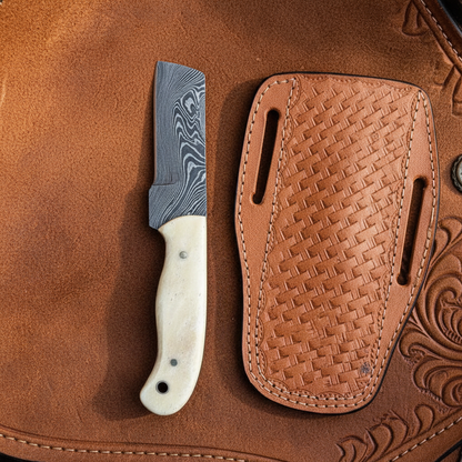 Damascus steel cowboy bull cutter knife on a leather saddle